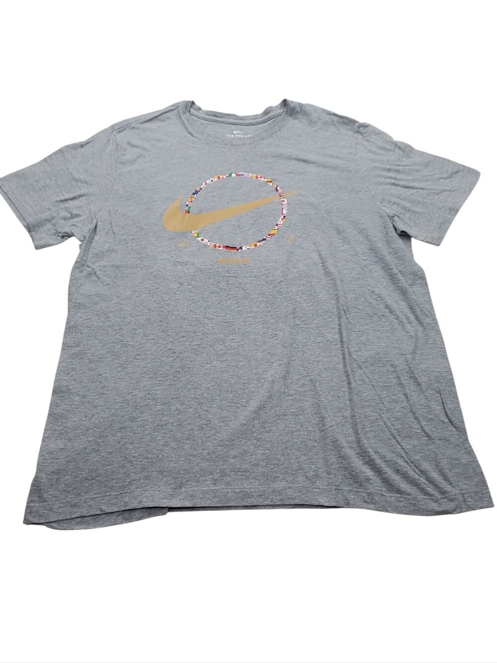 Nike 2020 Just Do It Olympic Light Gray Tee with Gold Swoosh and Flag Ring.